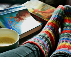 feet with cozy socks, books, and cup of coffee